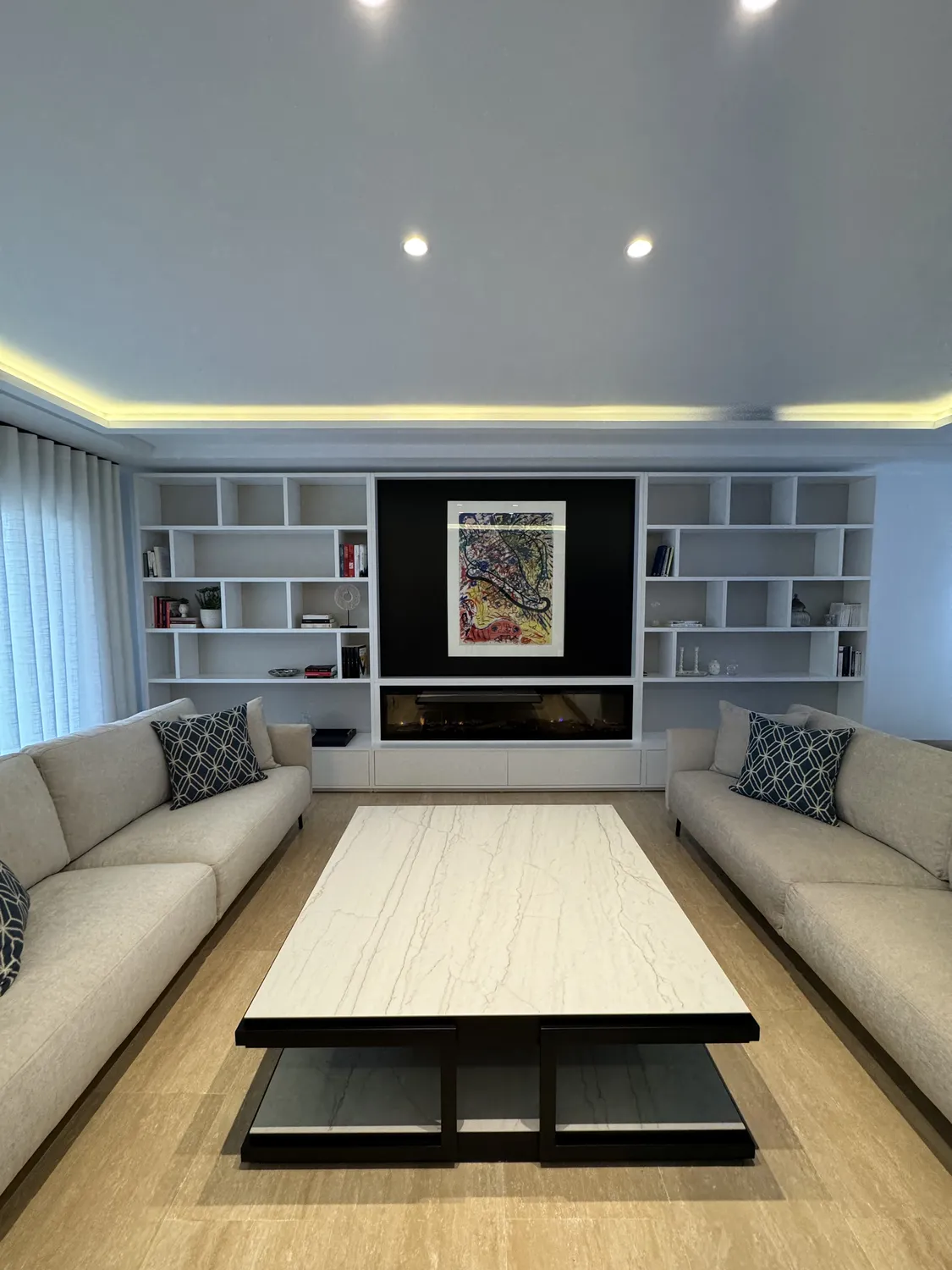 Salón con librería a medida, chimenea integrada e iluminación indirecta, vivienda en las rozas
