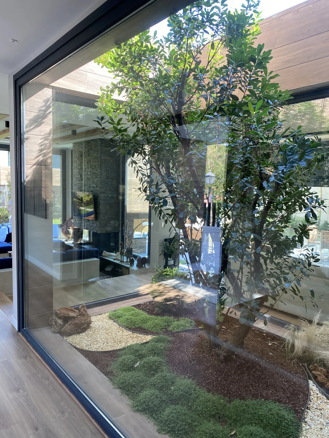 Patio interior ajardinado con grandes cristaleras, vivienda en Mirasierra
